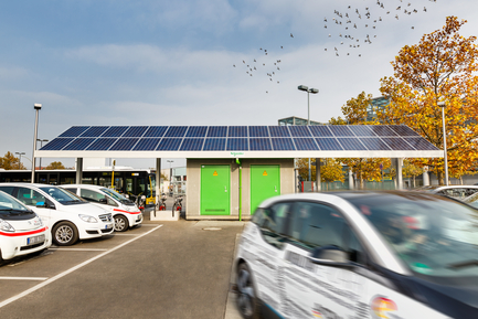 Elektroautos auf Parkplatz vor Bushaltestelle mit Aufdach-Photovoltaik